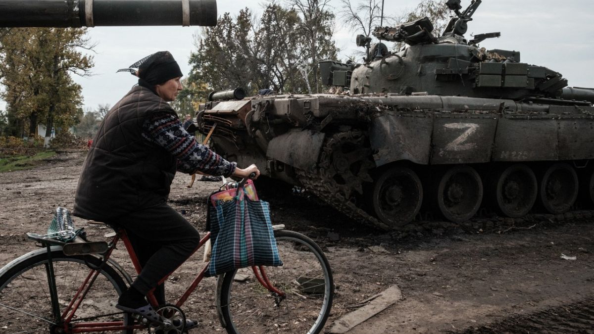 A local resident rides past an abandoned Russian tank marked Z in Kyrylivka, in the recently retaken area near Kharkiv, on September 30, 2022.