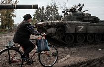 A local resident rides past an abandoned Russian tank marked Z in Kyrylivka, in the recently retaken area near Kharkiv, on September 30, 2022.