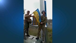 Dos soldados ucranianos colocan la bandera de Ucrania tras recuperar la ciudad de Limán, en Donetsk.