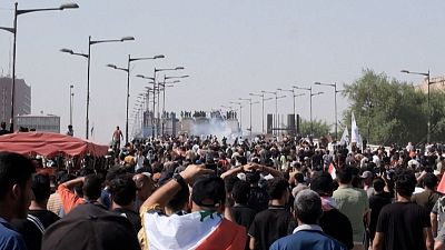 Iraqi anti-government demonstrators hurling stones at security forces