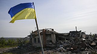Bandeira ucraniana em frente a casa destruída durante a invasão russa
