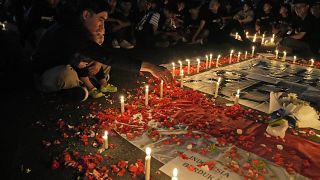 Люди приносят цветы и свечи к мемориалу в память о погибших в давке на стадионе в Маланге.