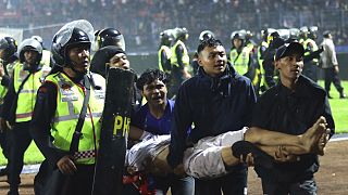Football fans carry an injured man following clashes during a match at Kanjuruhan Stadium in Malang, East Java, Indonesia, Saturday, Oct. 1, 2022.