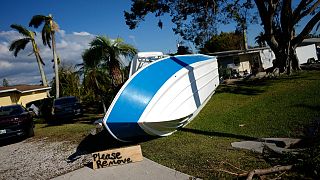 A sign placed by a resident asks that a boat that landed on their lawn during Hurricane Ian please be removed, in south Fort Myers, Fla., Saturday, Oct. 1, 2022.