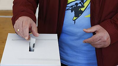 Un homme glissant son bulletin dans l'urne d'un bureau de vote à Sofia, dimanche 2 octobre 2022.