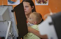 Женщина с ребёнком голосует на парламентских выборах в Болгарии