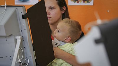 Женщина с ребёнком голосует на парламентских выборах в Болгарии