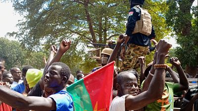 Protesters carry a Burkina Faso flag as soldiers stand atop a military vehicle during a demonstration in Ouagadougou on October 2, 2022.