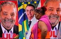 A woman walks past towels with images of Brazilian presidential candidates, President Jair Bolsonaro, center, and former President Luiz Inacio Lula da Silva
