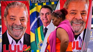 A woman walks past towels with images of Brazilian presidential candidates, President Jair Bolsonaro, center, and former President Luiz Inacio Lula da Silva