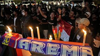 Aficionados al fútbol corean consignas durante una vigilia por los seguidores del Arema FC víctimas de los disturbios del sábado en Yakarta, Indonesia, el 2 de octubre de 2022
