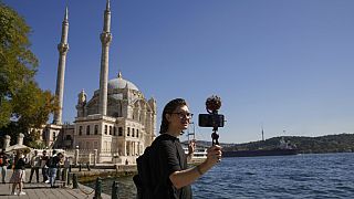 El youtuber Niki Proshin graba un vídeo para su canal de YouTube mientras pasea junto a la histórica mezquita de Ortakoy en Estambul
