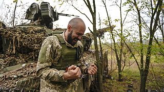 A Ukrainian soldier speaks to his brothers in arms while his unit waits for order to fire in Bakhmut, Ukraine, Sunday, Oct. 2, 2022.