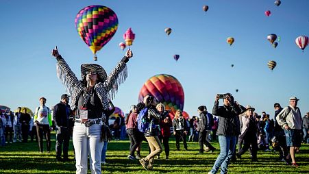 Nicole Tagart, a launch official with the 50th annual Albuquerque International Balloon Fiesta, signals a balloonist to take off.