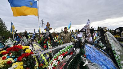 Украинский офицер у могилы на Аллее Героев на кладбище в Буче Киевской области 3 октября 2022 года на фоне российского вторжения в Украину