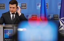 Volodymyr Zelenskyy adjusts his headphone as he participates in a media conference with NATO Secretary General Jens Stoltenberg at NATO headquarters in Brussels