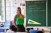 A teacher welcomes pupils in the classroom on the first day of the new academic at "Revolution Jet d'Eau" school in Marseille, southern France, on September 1, 2022.