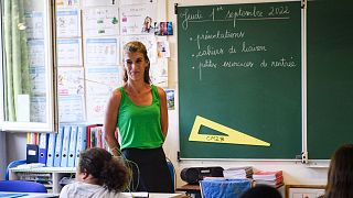 A teacher welcomes pupils in the classroom on the first day of the new academic at "Revolution Jet d'Eau" school in Marseille, southern France, on September 1, 2022.