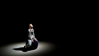 A performer looks up while sitting on stage in Budapest, Hungary