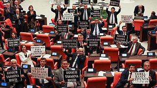 Opposition lawmakers in Turkey hold signs in protest against the new "disinformation" law.
