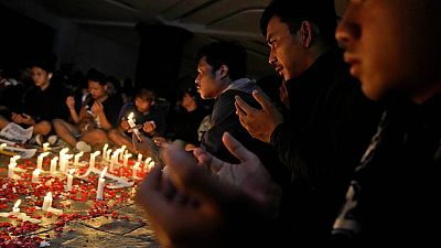 Soccer fans pray during a candle light vigil for the victims of Saturday's stampede