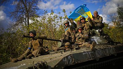 Soldados ucranianos sentados en un vehículo blindado mientras conducen por una carretera entre Izium y Limán, en Ucrania, el martes 4 de octubre de 2022.