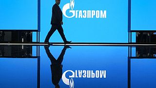 A man walks at an exhibition at the St. Petersburg International Gas Forum in St. Petersburg, Russia, Wednesday, Sept. 14, 2022, with a logo of Russian gas monopoly Gazprom in