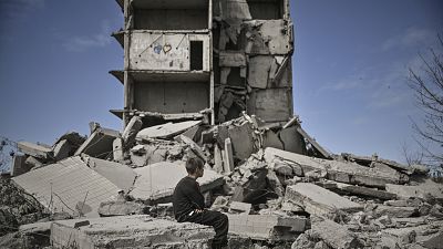 Un jeune garçon est assis devant un bâtiment détruit après un bombardement à Kramatorsk dans le Donbass