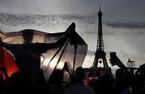 A supporter displays a French flag in the Paris fan zone in front of the Eiffel Tower during the Euro 2016 final soccer match between Portugal and France.