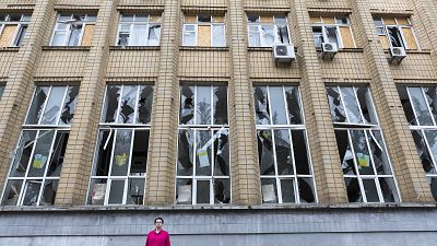 A woman stands in front of a damaged building after the Russian shelling in Mykolaiv, Ukraine