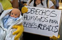 Des manifestants tenant des poupées de bébé et des pancartes sur lesquelles on peut lire "Droits humains pour les bébés volés" à Madrid, le 26 juin 2018.