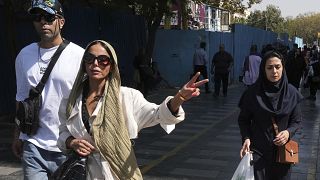 امرأة تومض بعلامة النصر وهي تتجول في البازار الرئيسي القديم في طهران - إيران. 2022/10/01