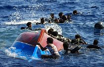  Migrants swim next to their overturned wooden boat during a rescue operation by Spanish NGO Open Arms, Aug. 11, 2022.