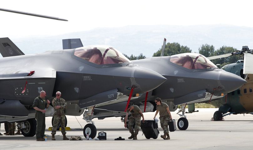 يعمل أفراد من الجيش الأمريكي بالقرب من طائرة مقاتلة من طراز F-35، متوقفة في القاعدة العسكرية بمطار سكوبيه، مقدونيا الشمالية، يوم الجمعة 17 يونيو/حزيران 2022. 