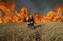 A journalist runs from a burning wheat field during his assignment after Russian shelling, a few kilometres from Ukrainian-Russian border in the Kharkiv region, July 29, 2022.