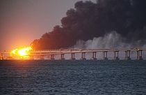 Las llamas y el humo se elevan frente al puente de Crimea que conecta el territorio continental ruso y la península de Crimea sobre el estrecho de Kerch, en Kerch, Crimea