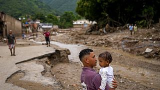 Ένας άνδρας με την κόρη του στην αγκαλιά μετά τις κατολισθήσεις στην πόλη Τεχερίας στη Βενεζουέλα
