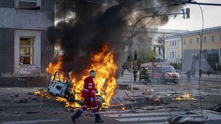 عامل إنقاذ أمام سيارة محترقة في العاصمة الروسية كييف 