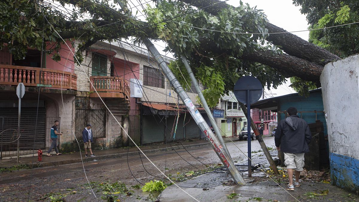 Los residentes caminan bajo los postes eléctricos rotos por los vientos huracanados de Julia en Bluefields, Nicaragua, el 9 de octubre de 2022. 