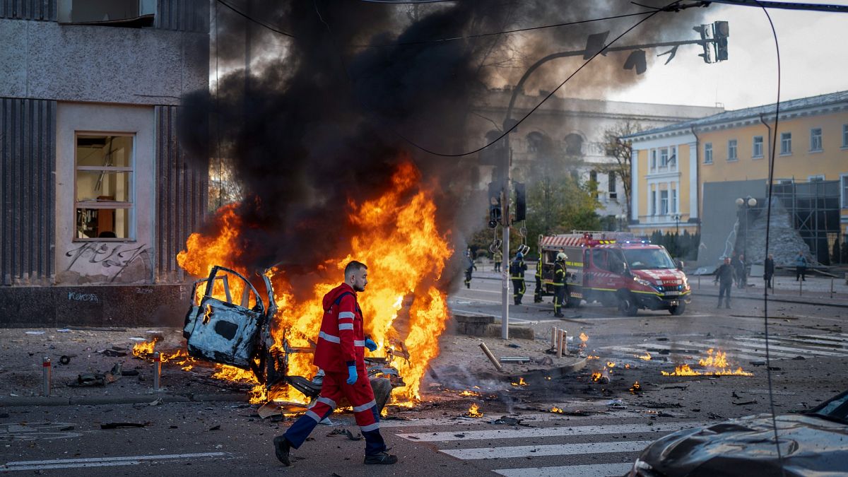 A medical worker runs past a burning car after a Russian attack in Kyiv, Ukraine, on Monday