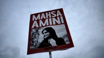 A woman holds a placard with a picture of Iranian Mahsa Amini as she attends a protest against her death, in Berlin, Germany.