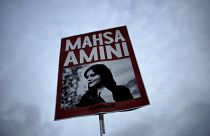A woman holds a placard with a picture of Iranian Mahsa Amini as she attends a protest against her death, in Berlin, Germany.