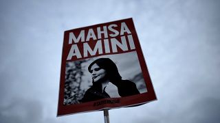 A woman holds a placard with a picture of Iranian Mahsa Amini as she attends a protest against her death, in Berlin, Germany.