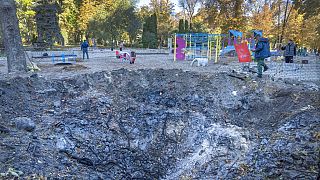 A man passes past a rocket crater at playground in city park in Kyiv, Ukraine.