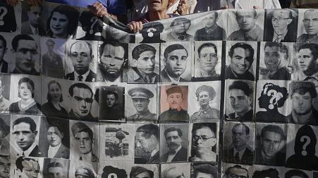 A protestor holds up a banner showing victims of the Spanish Civil War