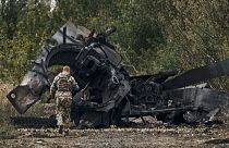 Ukrán katona egy kiégett orosz tank roncsa mellett