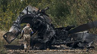 Ukrán katona egy kiégett orosz tank roncsa mellett