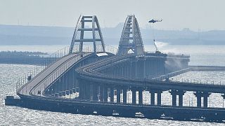 FILE - A helicopter drops water to stop fire on the Crimean Bridge connecting Russian mainland and Crimean peninsula over the Kerch Strait, in Kerch, Crimea, Oct. 8, 2022.