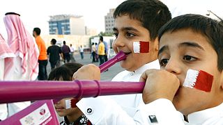 فتيان قطريون رسموا وجوههم بألوان علمهم الوطني في سوق الدوحة التقليدي، في قطر