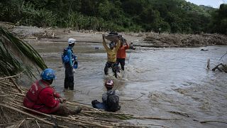 Rescuers cross the Tuy river as they search for victims of a devastating landslide in the Venezuelan town of Las Tejerias.